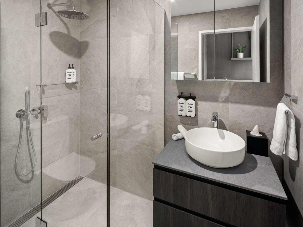 a bathroom with a sink and a glass shower at The Sebel Canberra Campbell in Canberra