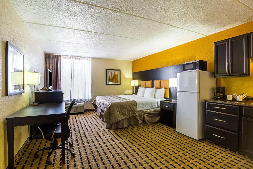 ein Hotelzimmer mit einem Bett, einem Schreibtisch und einem Kühlschrank in der Unterkunft Clarion Pointe Lake Jackson - Clute in Lake Jackson