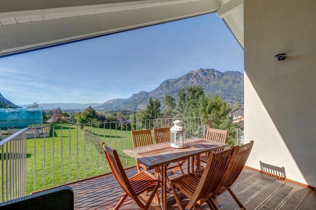 un tavolo e sedie su una terrazza con una grande finestra di La Vougerotte - Terrasse Vue Montagnes a Vougy