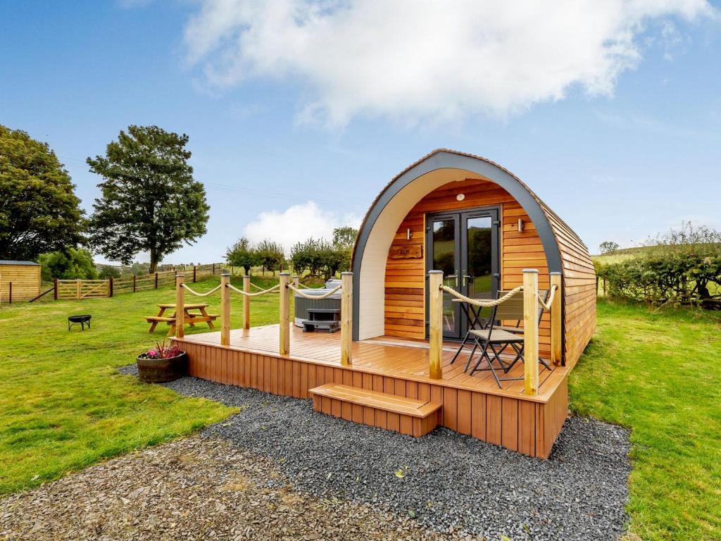 a small wooden cabin with a deck in a field at Elm-uk36259 in Llanfair Caereinion