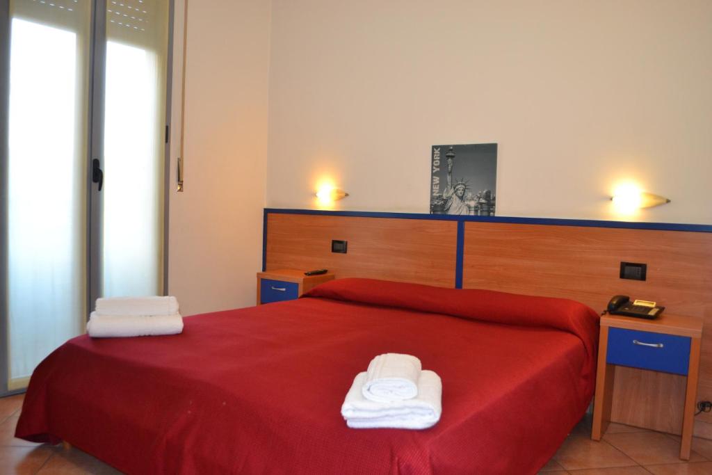 a bedroom with a red bed with two towels on it at Hotel Iride in Milan