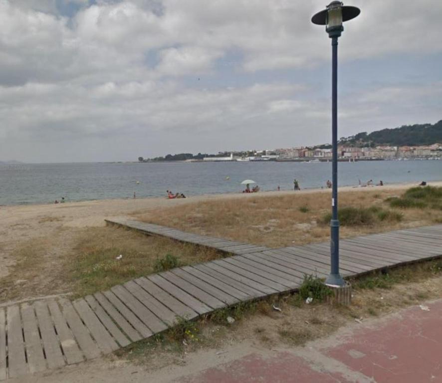 a light pole next to a beach with people in the water at Apartment - 2 Bedrooms - 0137 in Cangas de Morrazo