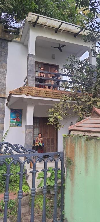 dos personas sentadas en un balcón de una casa en ABRU'S Holidays Foreign travelers, en Alleppey