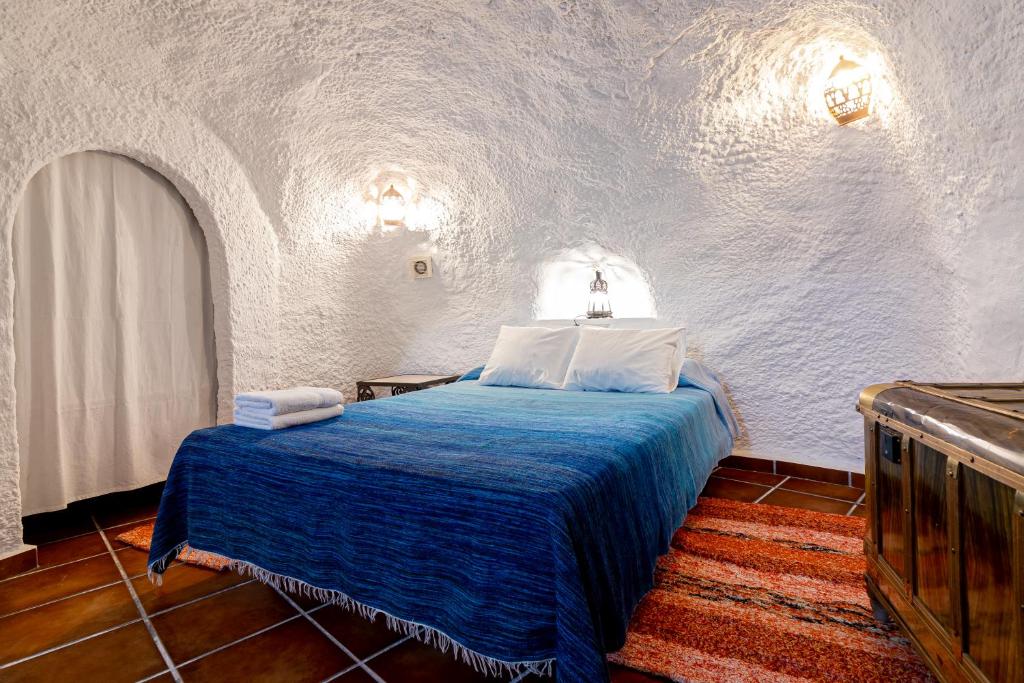 a bedroom with a blue bed in a white room at Cuevas El Abanico - VTAR vivienda turística de alojamiento rural in Granada