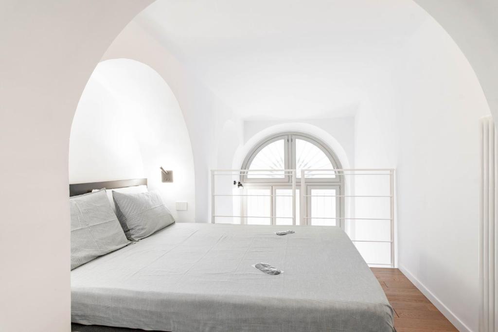 ein weißes Schlafzimmer mit einem Bett und einem Bogenfenster in der Unterkunft Dream Loft in Turin