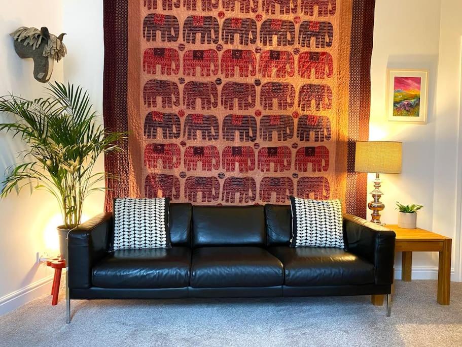 um sofá de couro preto numa sala de estar com uma parede em The Wee Bunk House - Innerleithen em Innerleithen