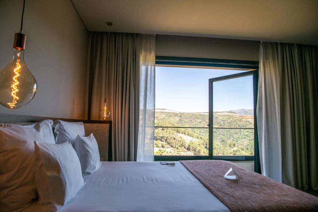 a bedroom with a large bed and a large window at MW Douro Wine & Spa Experience Hotel Collection in Santa Marta de Penaguião