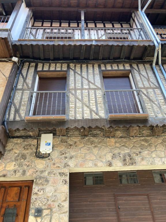 an old stone building with two windows and a door at Monforte de la Sierra - Acogedora y cálida vivienda 