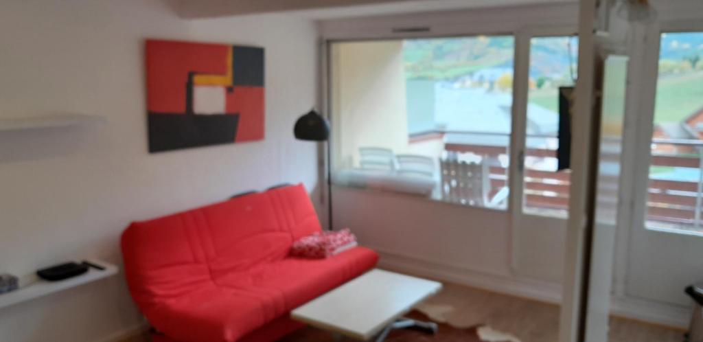 a living room with a red couch and a table at Appartement 2 ch 40 m2 au pied des pistes de ski in Enchastrayes