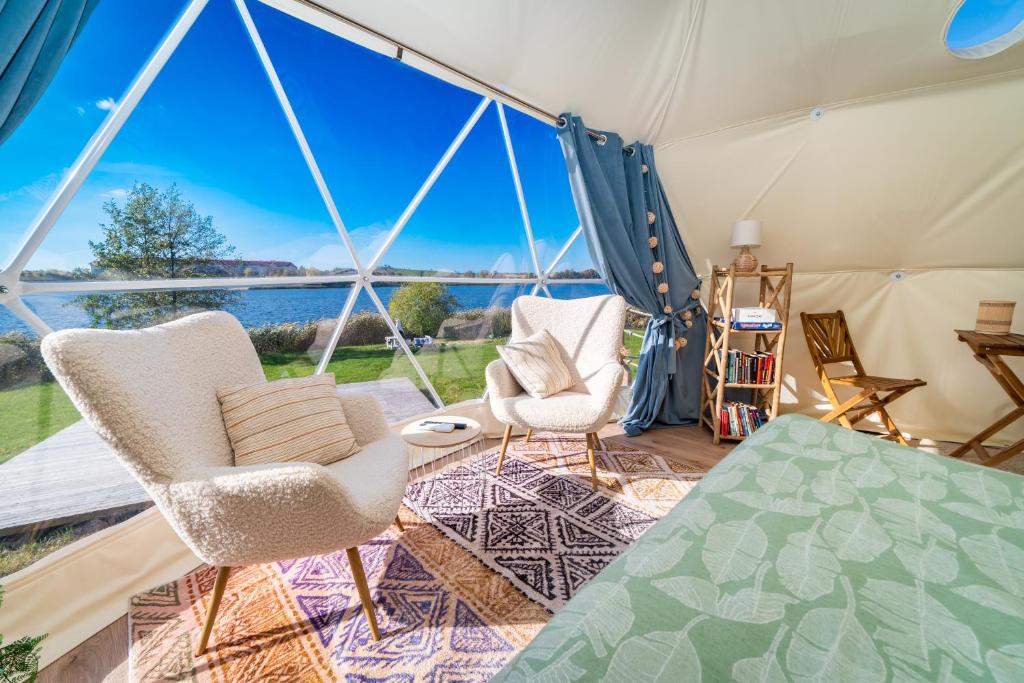Lake Glamp Mikołajki - Adults Only في ميكووايكي: غرفة بها كرسيين وخيمة مطلة