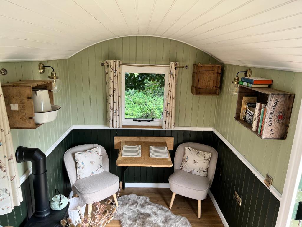 Berwick Saint JamesにあるStonehenge Campsite & Glampingの小さな客室で、椅子2脚、テーブル、窓が備わります。