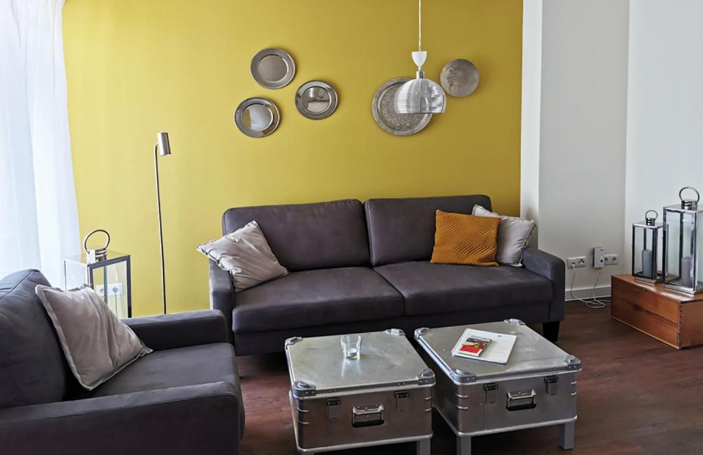 ein Wohnzimmer mit einem schwarzen Sofa und einer gelben Wand in der Unterkunft Dautzenberg Ferienapartments in Bad Neuenahr-Ahrweiler