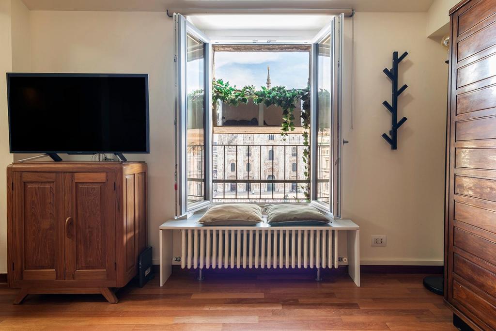 een woonkamer met een tv en een raam bij easyhomes Duomo View in Milaan