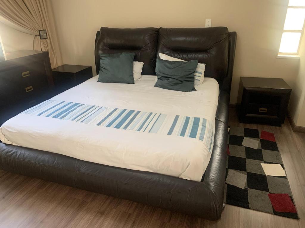 a bed with a black leather headboard in a room at Safari Deluxe Rooms - elegant rooms with access to beautiful garden & pool in Roodepoort