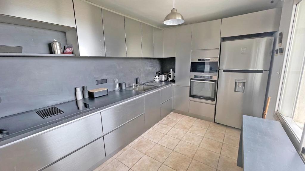 a kitchen with white cabinets and stainless steel appliances at Miremer in Sainte-Maxime