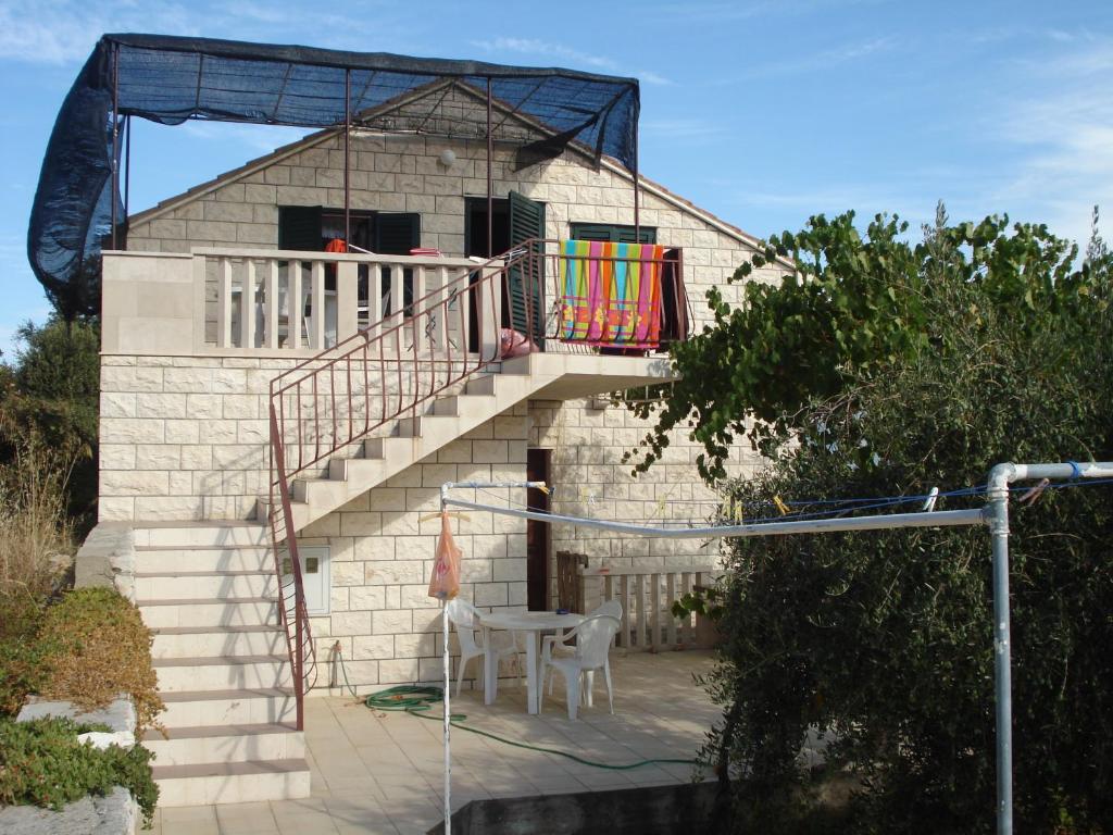 a house with a staircase with a table and a balcony at Apartments Duka in Lumbarda