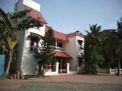 ein großes weißes Haus mit rotem Dach in der Unterkunft Alps Residency in Madurai