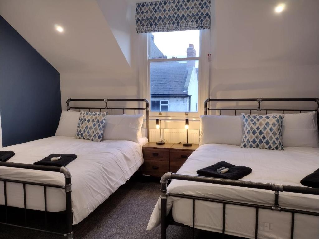 two beds in a room with a window at Printer's Apartment in Pontefract