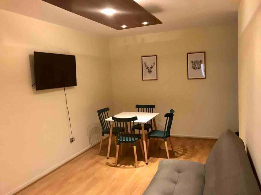 Una sala de estar con una mesa y un televisor. en Central y cómodo Depto en Providencia, en Santiago