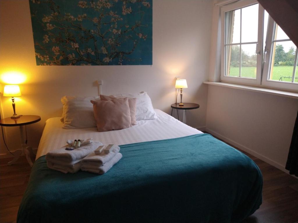 een slaapkamer met een bed met handdoeken en een raam bij B&B-Hotel de Joremeinshoeve in Kaatsheuvel