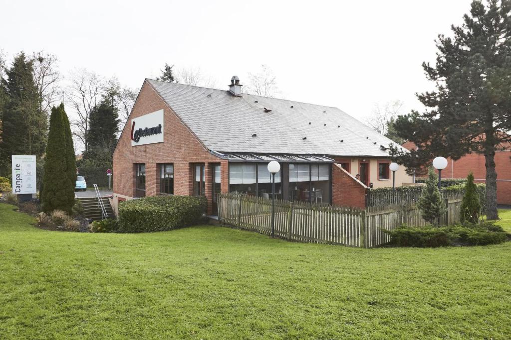 une maison en briques avec une clôture dans une cour dans l'établissement Campanile Lille Sud - CHR, à Lille