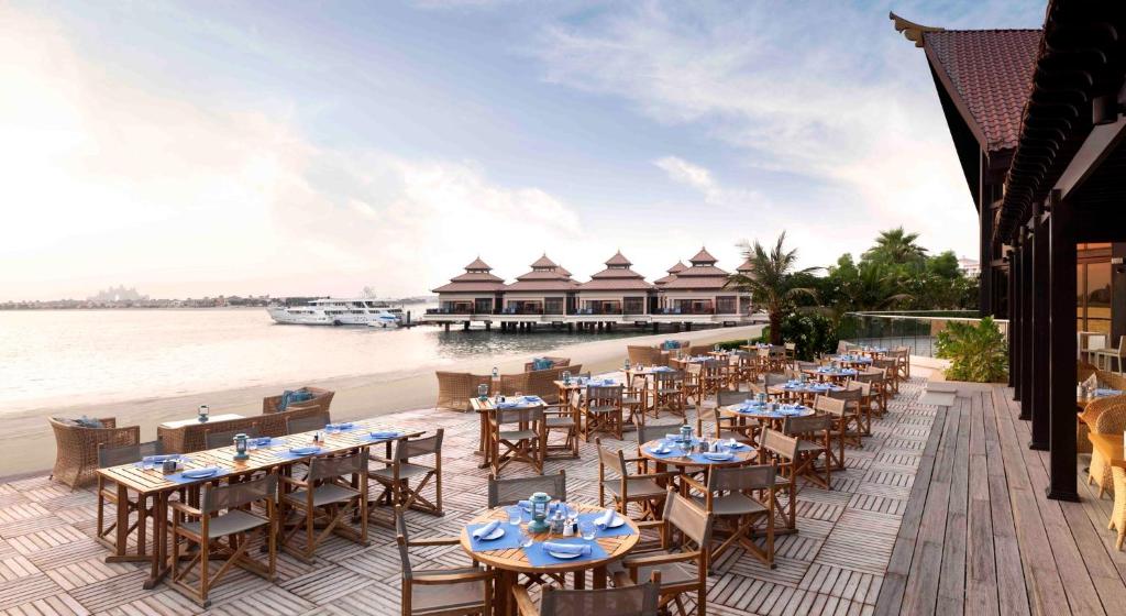 a restaurant on the beach with tables and chairs at Royal Amwaj Apartments, Palm Jumeirah, Free beach and pool access in Dubai