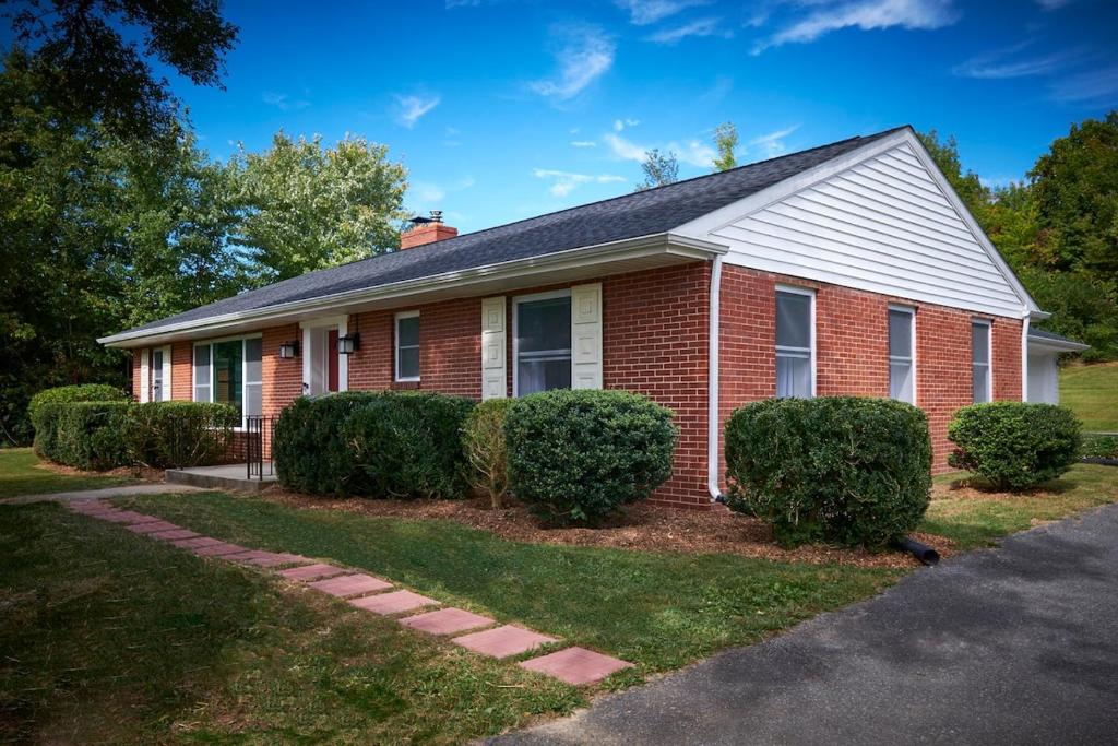 a red brick house with bushes in front of it at Fabulous Home W Outdoor Kitchen, Fire Pit And Back Yard! in Morristown