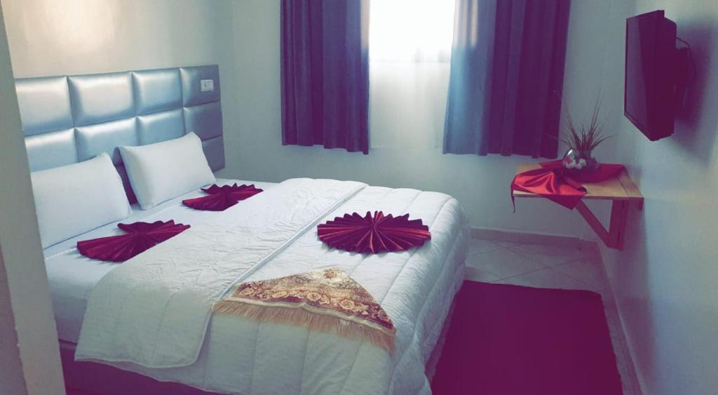 Un dormitorio con una cama con almohadas rojas. en Hotel Soukina, en Dakhla