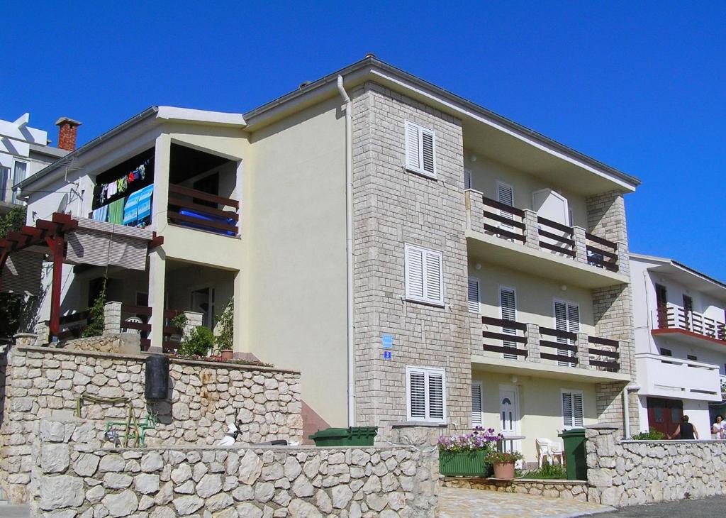 a large white building with a stone wall at Apartments Pavicic Marija in Pag