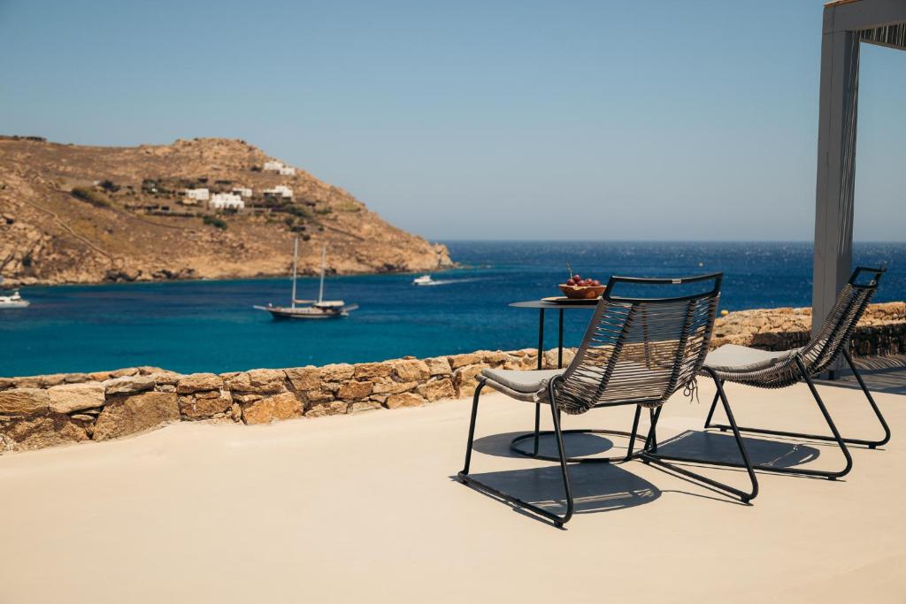 two chairs and a table on a patio overlooking the water at Nimbus My Aktis in Super Paradise Beach