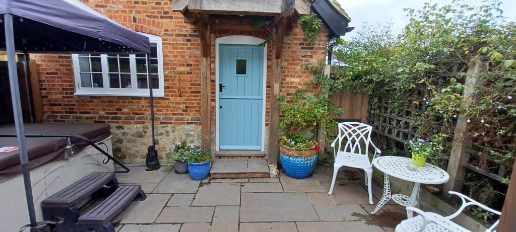 a patio with a blue door and white chairs at The Annexe with Hot Tub in Maidstone