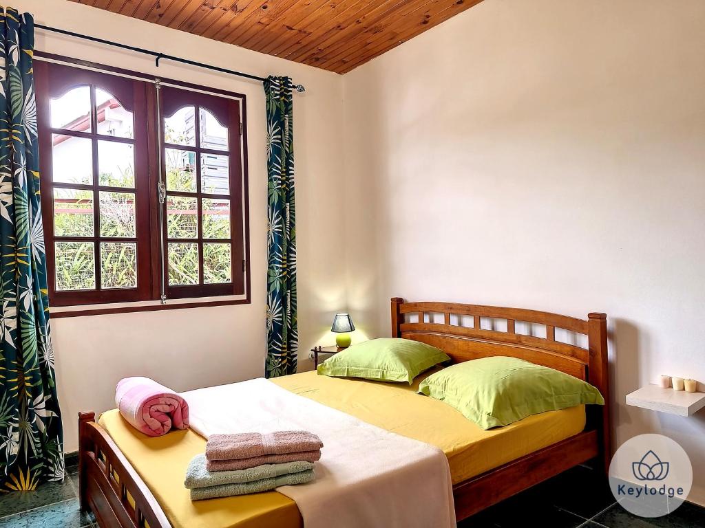 um quarto com uma cama e uma janela em Kaz'A Olymp - classé 3 étoiles - Maison de vacances à l'Entre-Deux em Entre-Deux