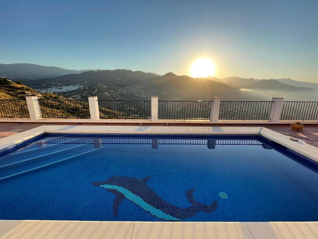uma piscina com um logótipo de golfinho com o pôr-do-sol em B&B Casa El Viaje em Cómpeta
