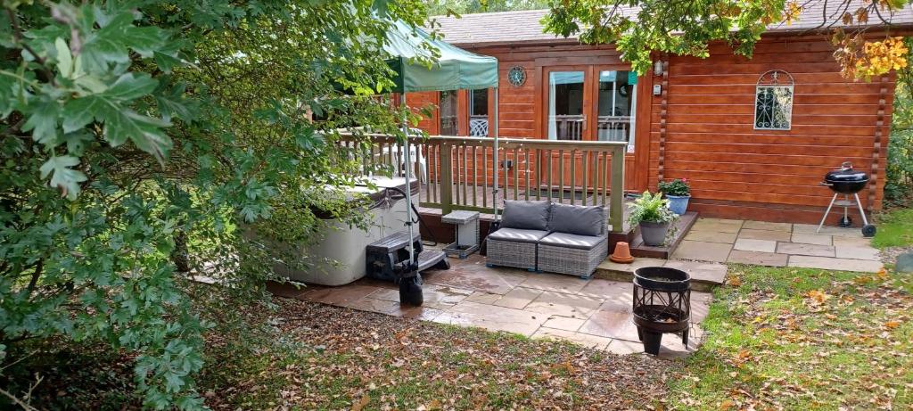 a backyard patio with a chair and a grill at The Cabin with Hot Tub in Maidstone