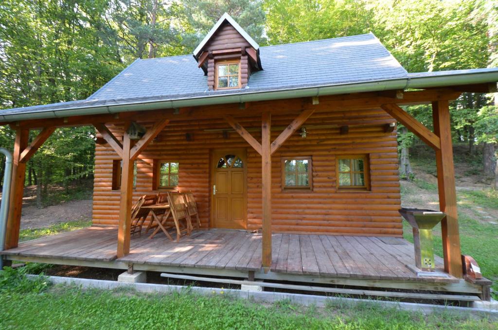 une cabane en rondins avec une terrasse couverte et une table sur une terrasse dans l'établissement Meadow Ranch Holiday Home, à Jaroslavické Paseky