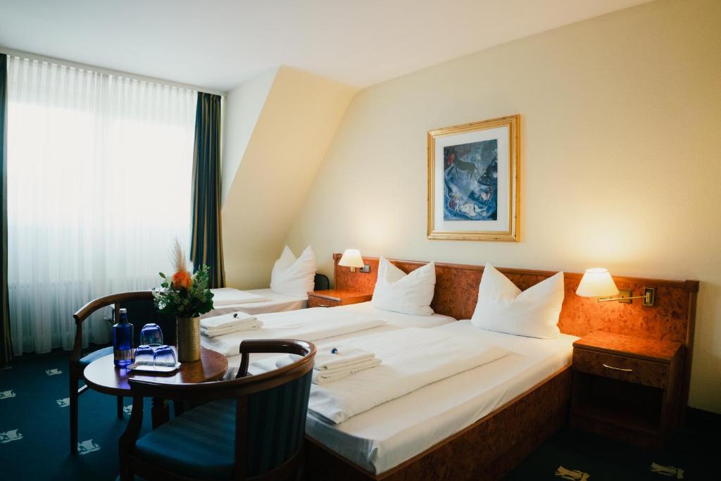 a hotel room with a large bed and a table at Altstadt Hotel St. Georg in Düsseldorf