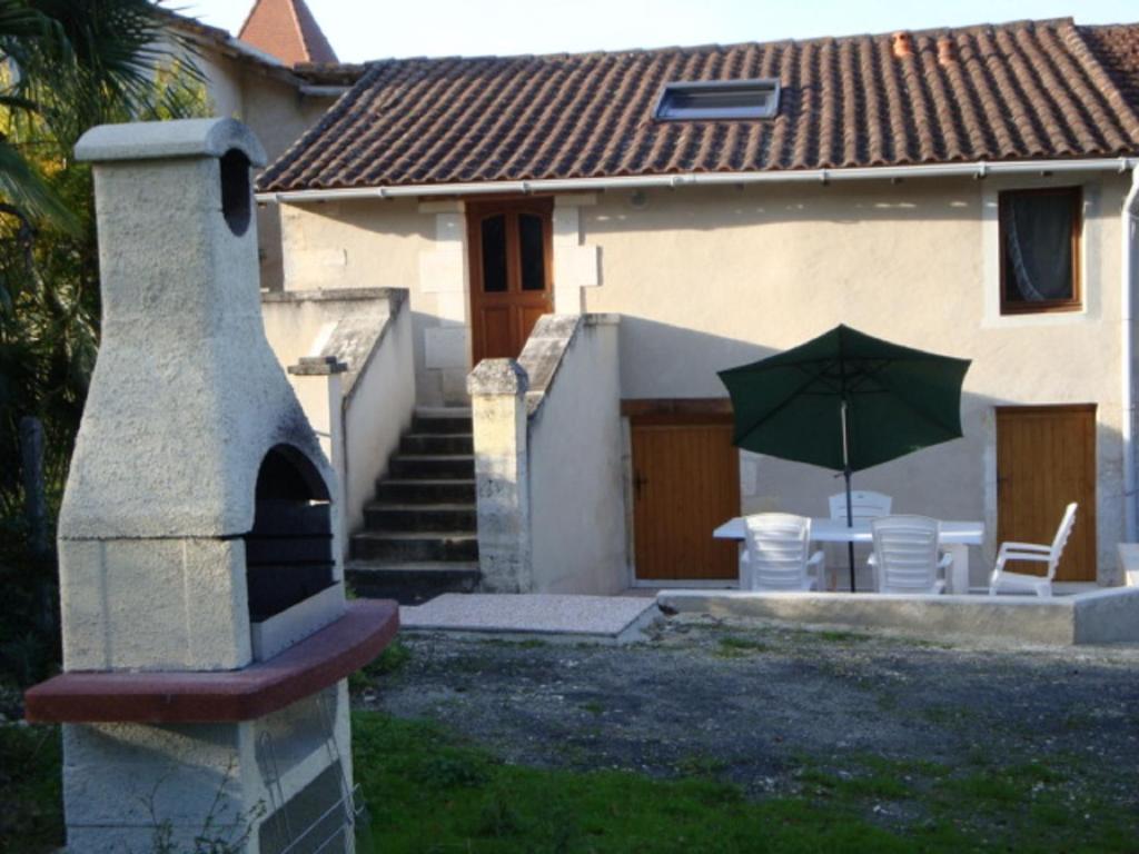 Casa con patio con sombrilla verde en Fermette Rénovée, en Celles