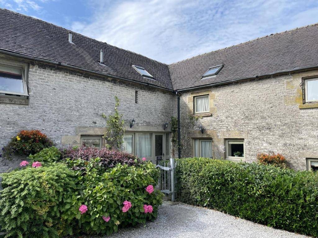ein altes Backsteinhaus mit einem Tor und Blumen in der Unterkunft Ollerenshaw Cottage in Buxton