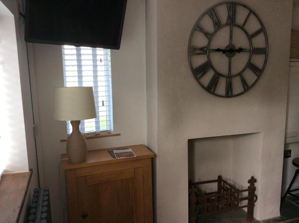 a clock on a wall next to a fireplace at Tremeer Cottage in Upper Beeding