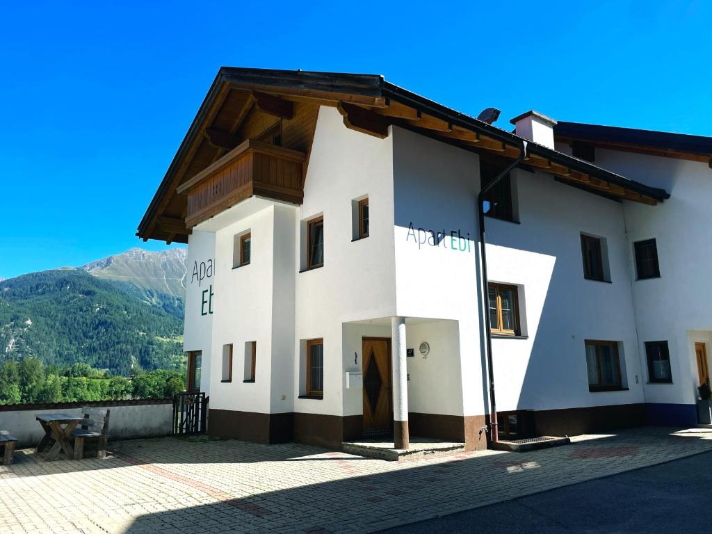 a white building with a wooden roof at Jägerlodge Apartments in Ladis