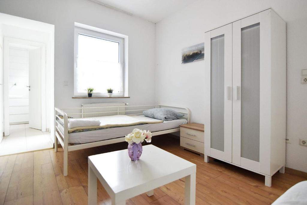 Work and Stay Troisdorf في ترويسدورف: غرفة مع سرير وطاولة مع إناء من الزهور