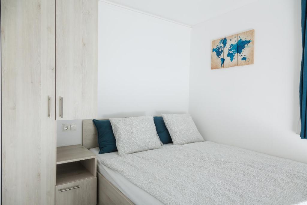 een witte slaapkamer met een bed met blauwe kussens bij Aranyos Hillside in Nagymaros