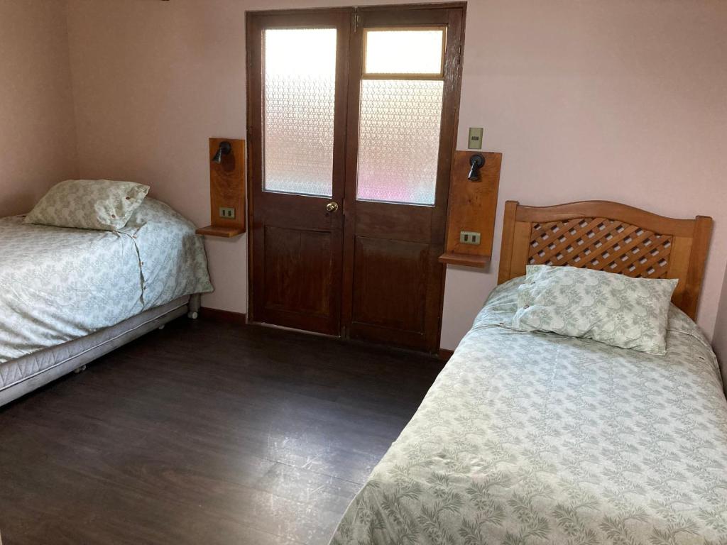 a bedroom with two beds and a door with a window at Hostel El Bajo in Iquique