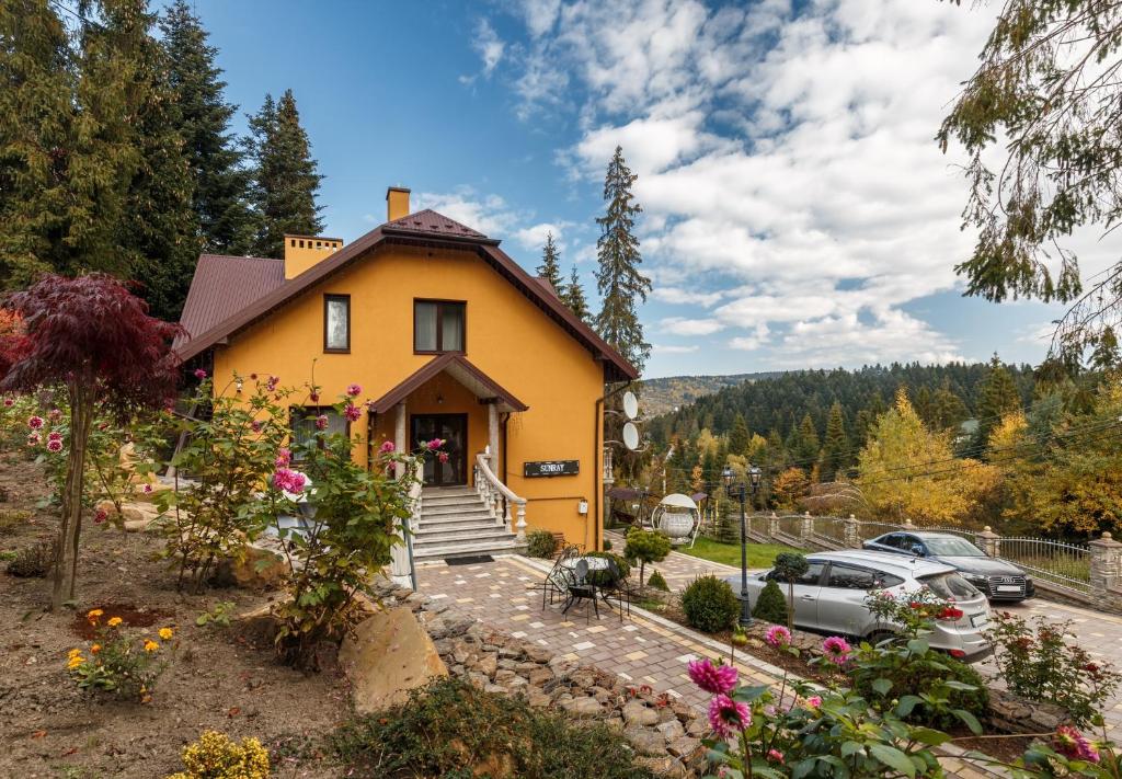 ein gelbes Haus mit einem davor geparkt in der Unterkunft Апарт- готель SunRay in Schidnyzja