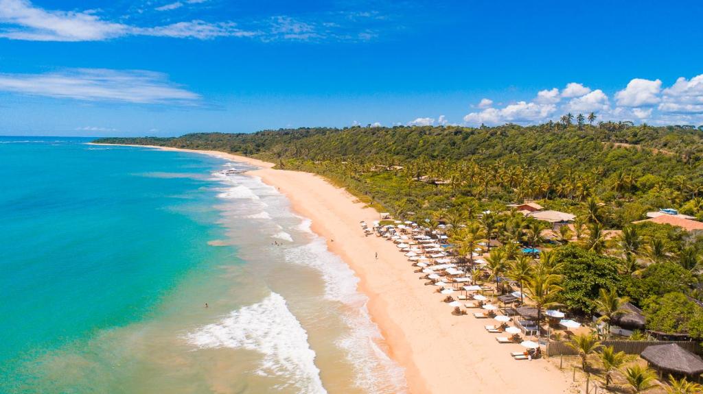 an aerial view of a beach with umbrellas and the ocean at Travel Inn Pousadas & Beach Club Trancoso in Trancoso