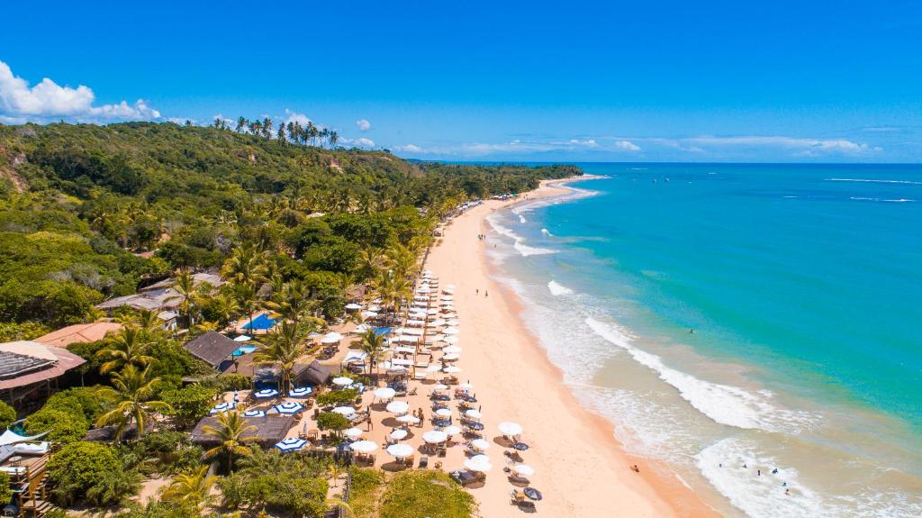 an aerial view of a beach with umbrellas and the ocean at Travel Inn Trancoso Suítes in Trancoso