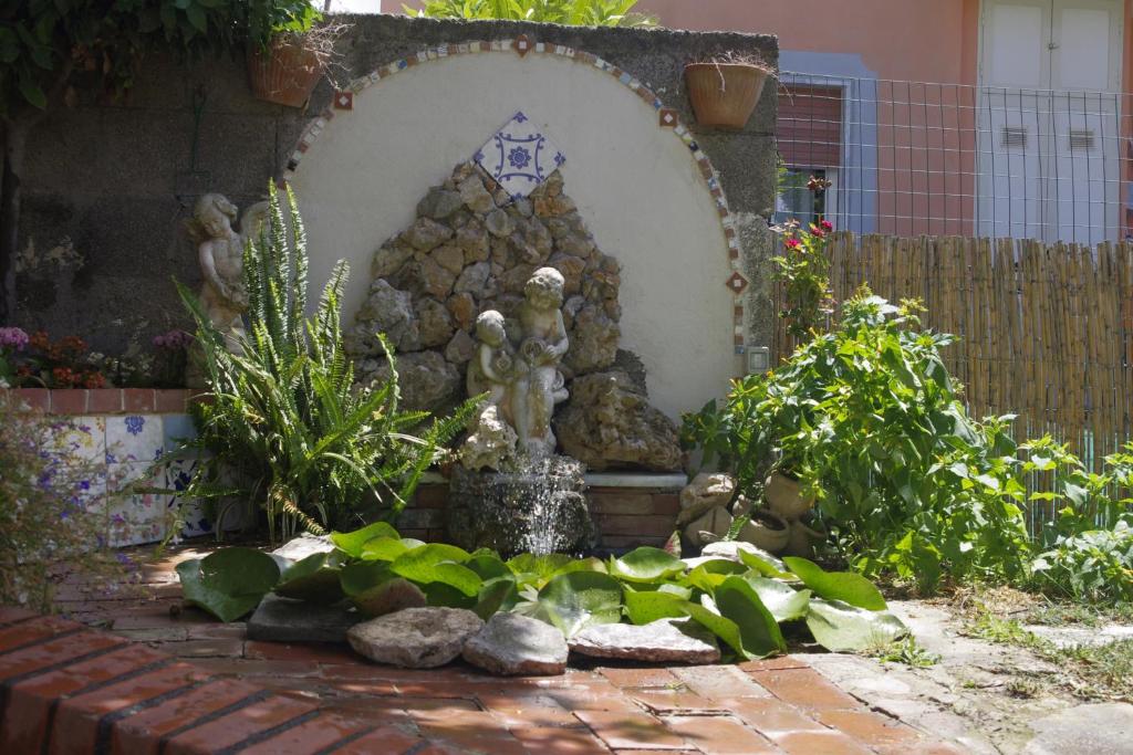a stone fountain in a garden with plants at Ninfea Apartment in Vico Equense