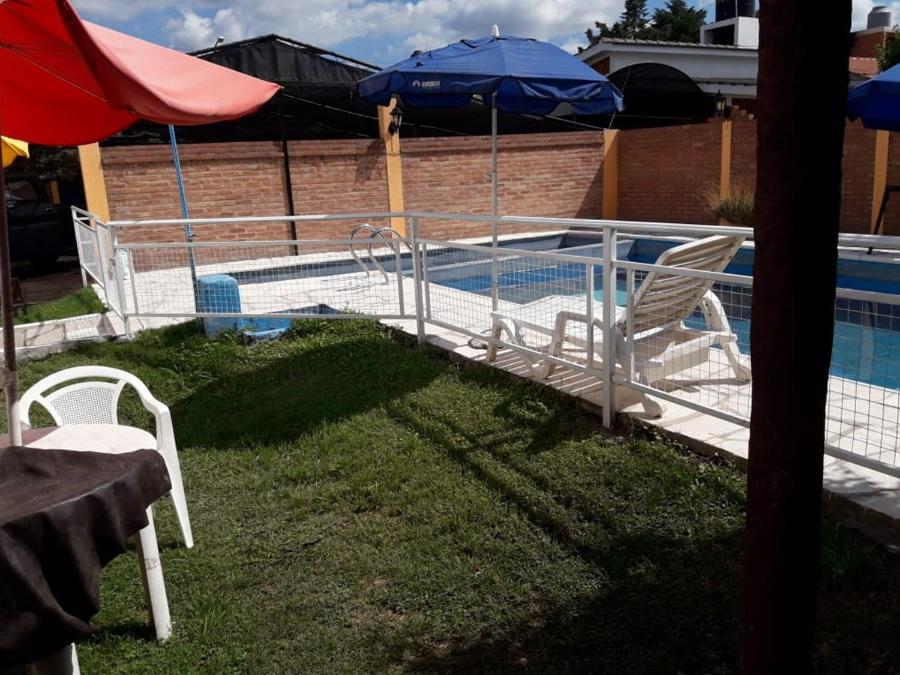 a swimming pool with two chairs and an umbrella at Posada Los Arcos in Villa Cura Brochero