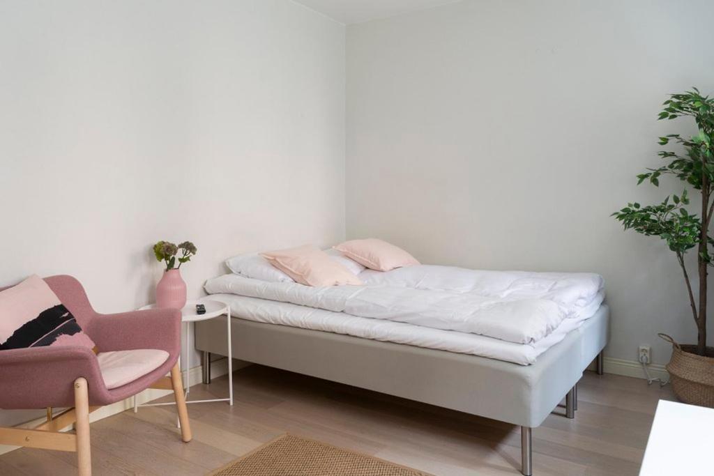 ヘルシンキにある2ndhomes Cozy Studio in the City Centerのベッドルーム1室(ベッド1台、ピンクの椅子付)