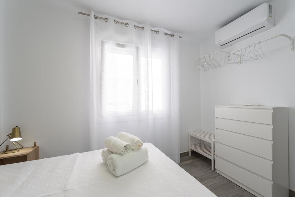 biała sypialnia z łóżkiem i komodą w obiekcie Apartamentos Joya del Mar w mieście Torre del Mar